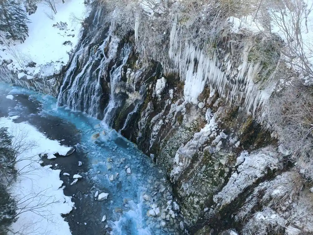 Frozen waterfall with icicles and blue stream