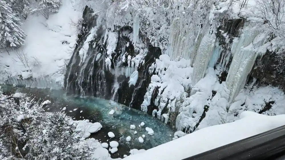 Frozen waterfall with icicles and turquoise water below
