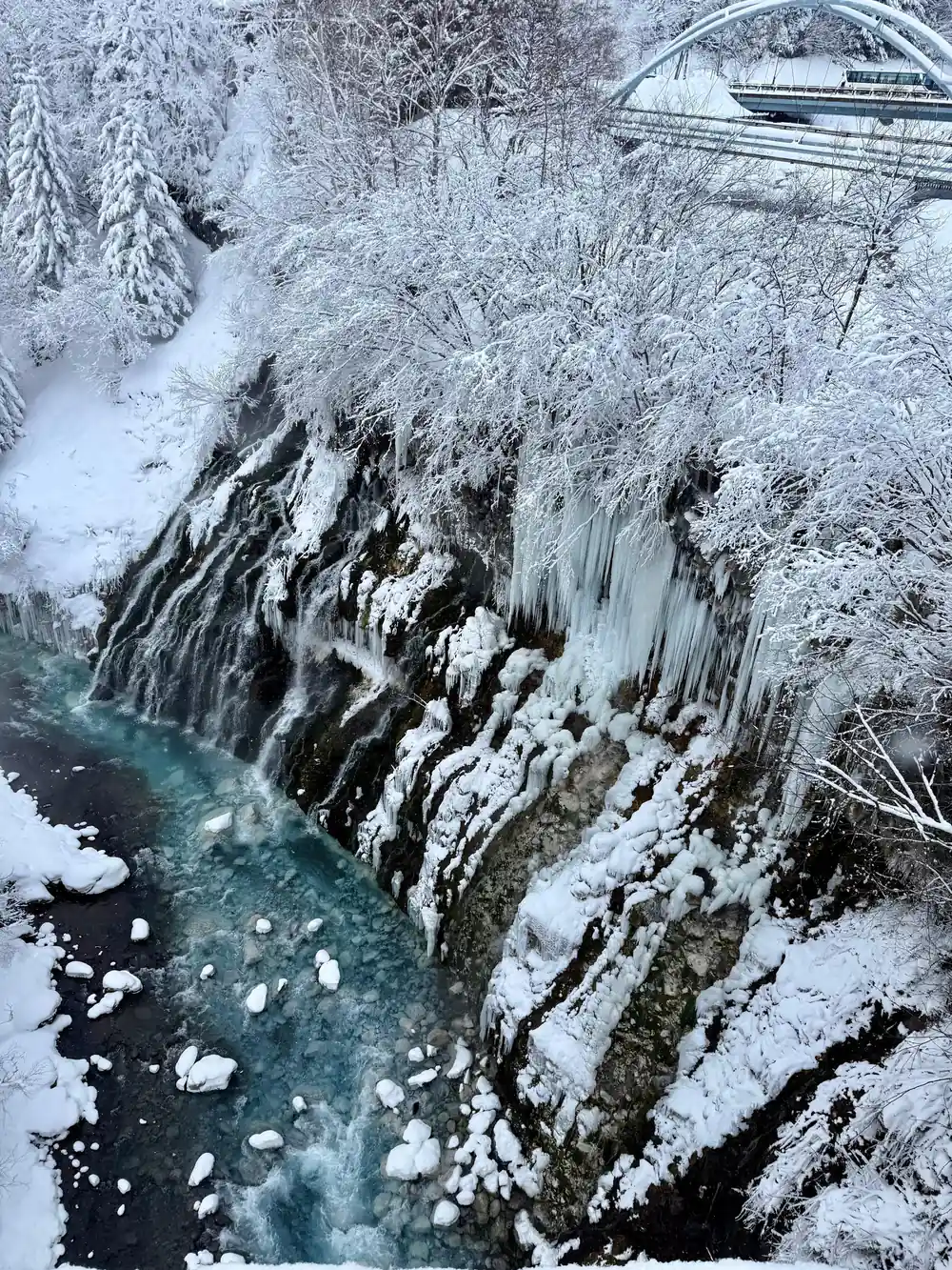 Frozen waterfall with turquoise water and snow-covered rocks