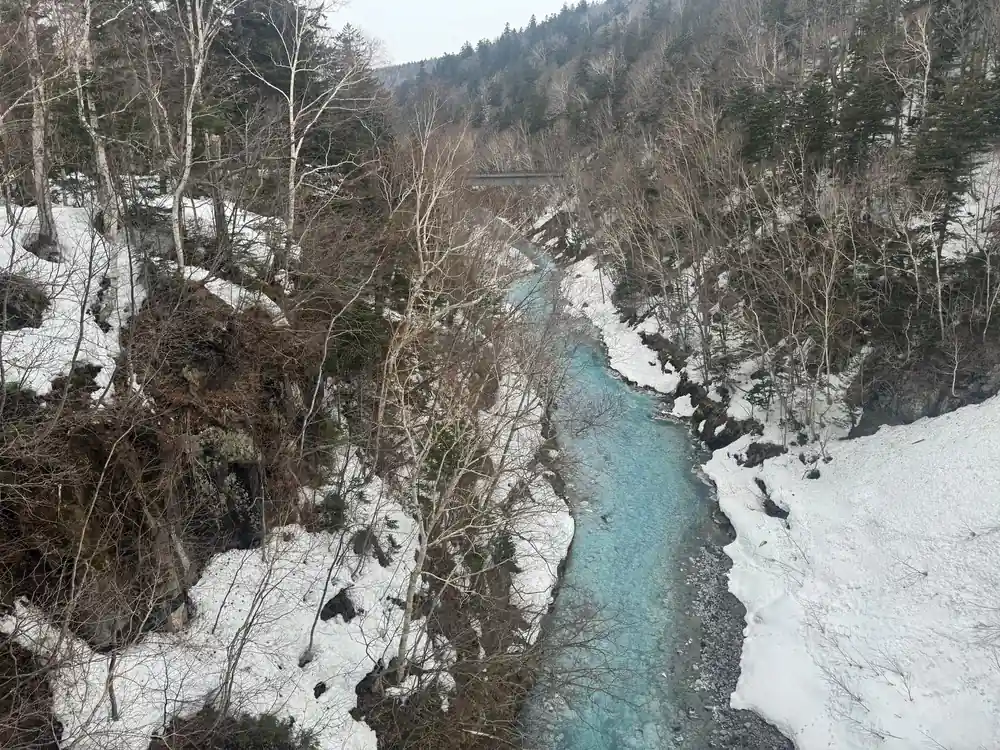 Turquoise river flowing through snow-covered rocky canyon