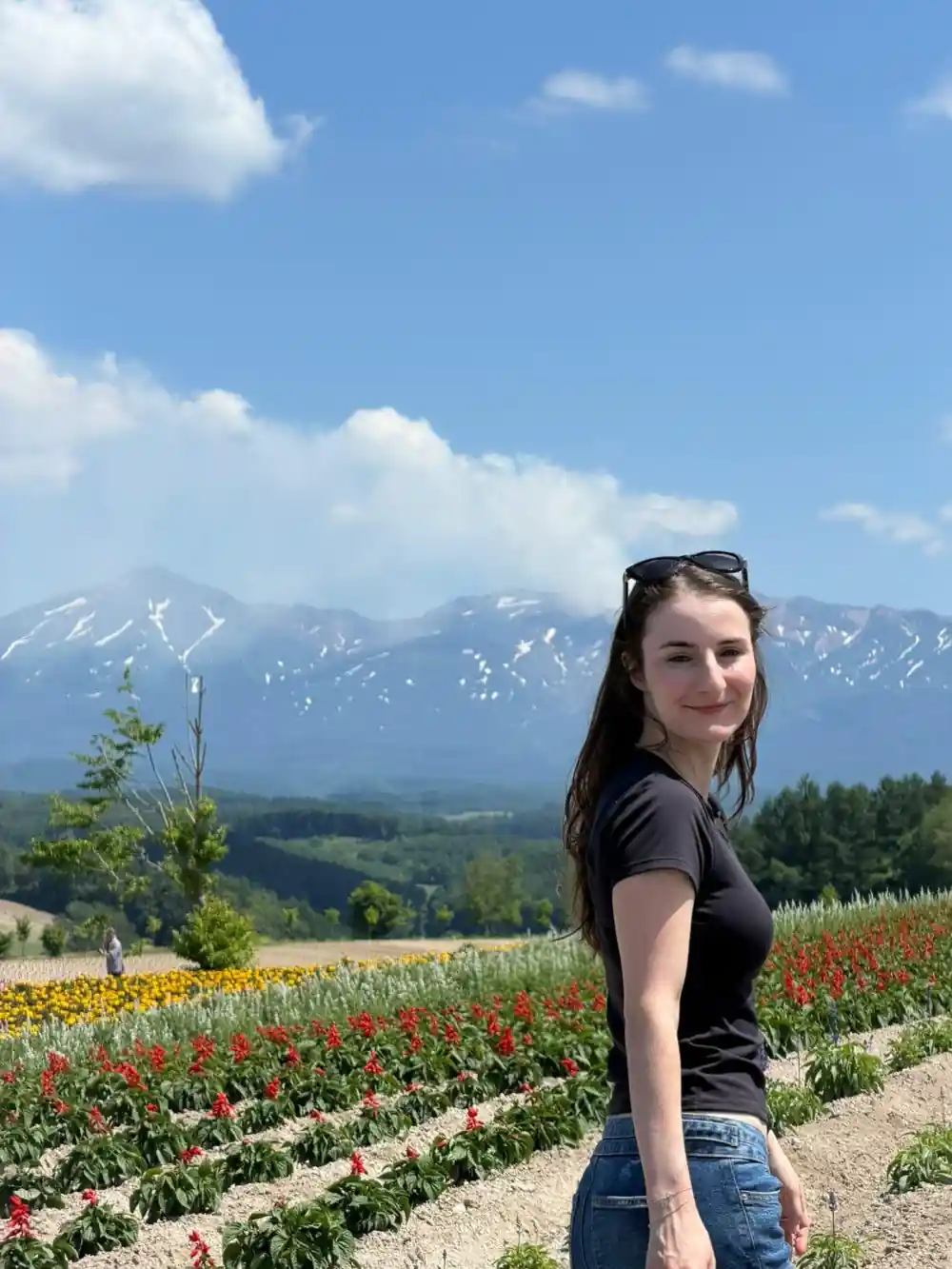 Woman posing in flower field with snow-capped mountain backdrop