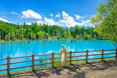 Woman in yellow jacket viewing turquoise lake with forest